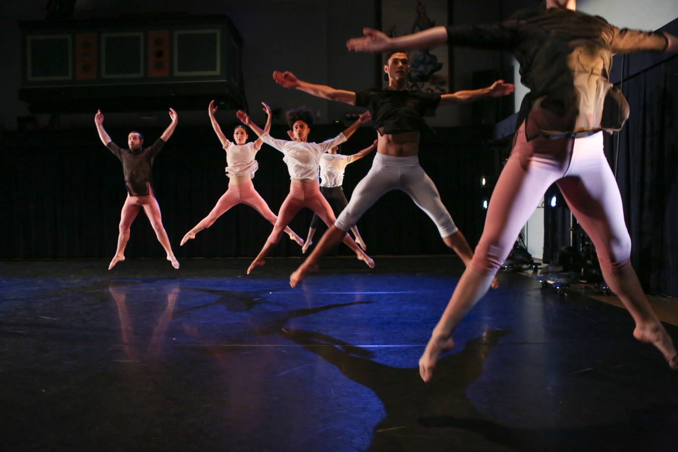 A group of dancers jump, their bodies like Xes